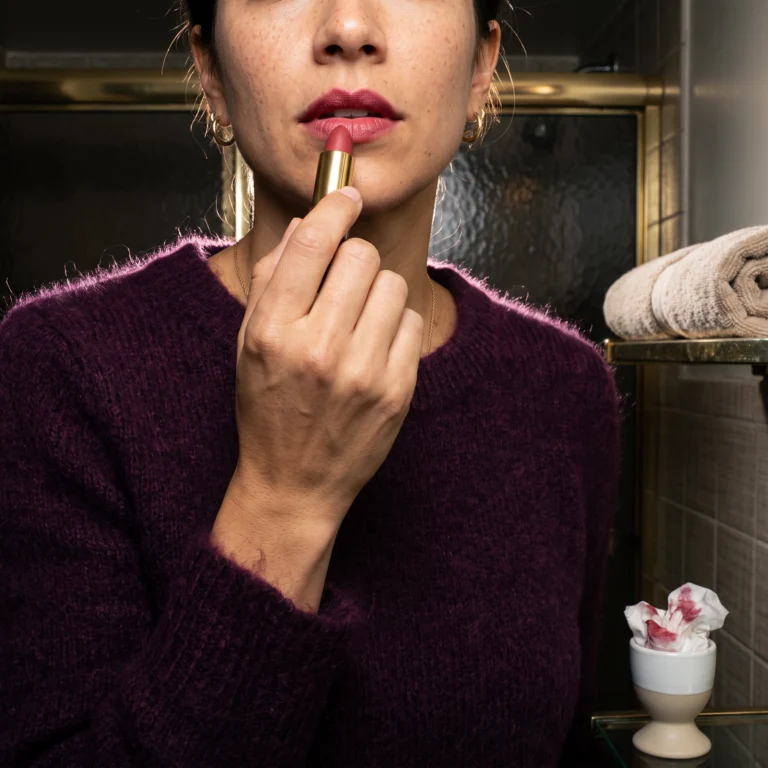 Avery, Beautyisles AI host, applies the best lipstick under a single bare bulb, matte and blotted at the centre