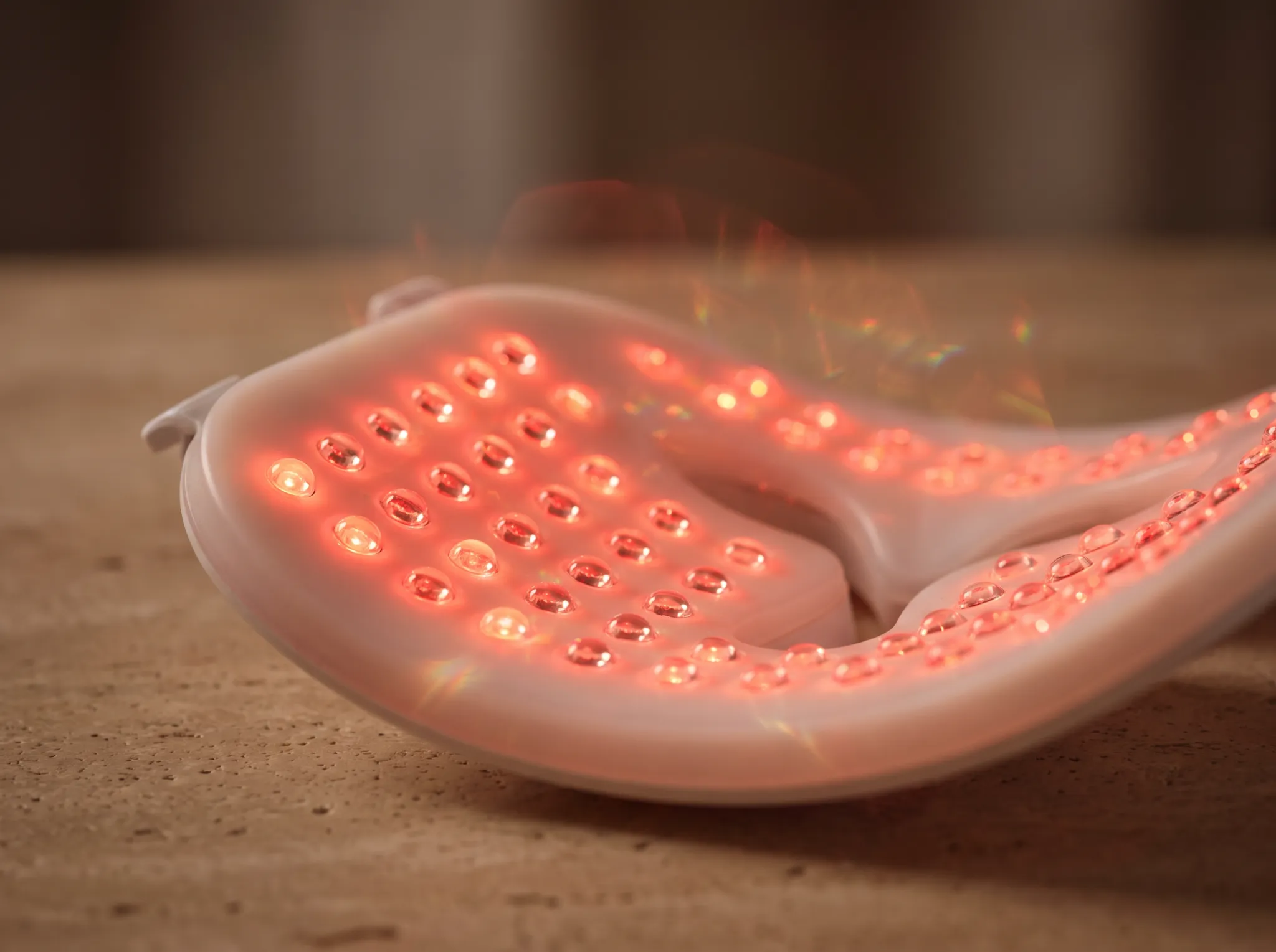 Close-up macro photography of clinical medical-grade LED diode optical matrix emitting ruby red and near-infrared light on travertine stone