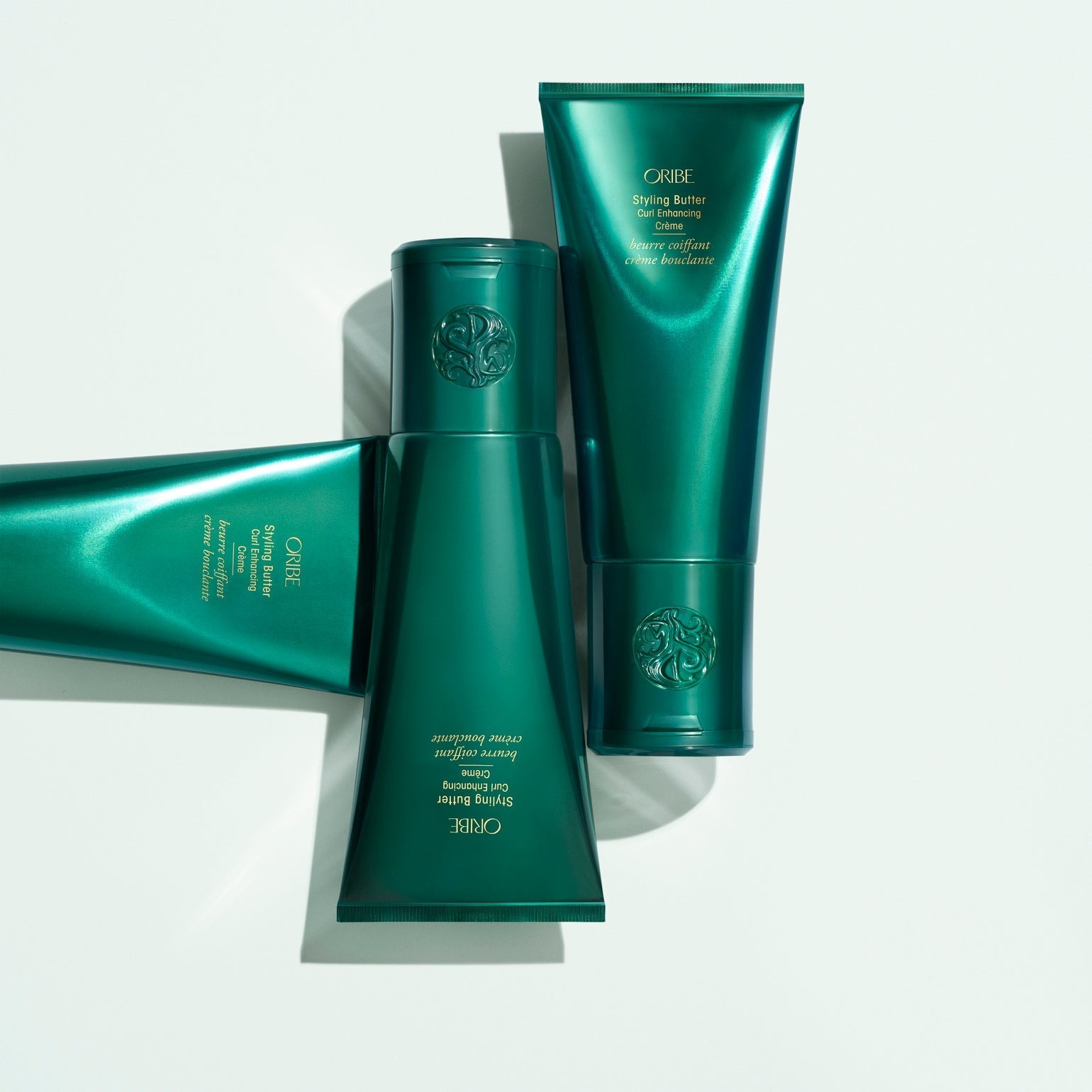 Oribe Styling Butter Curl Enhancing Creme green tube group on a clean white background.