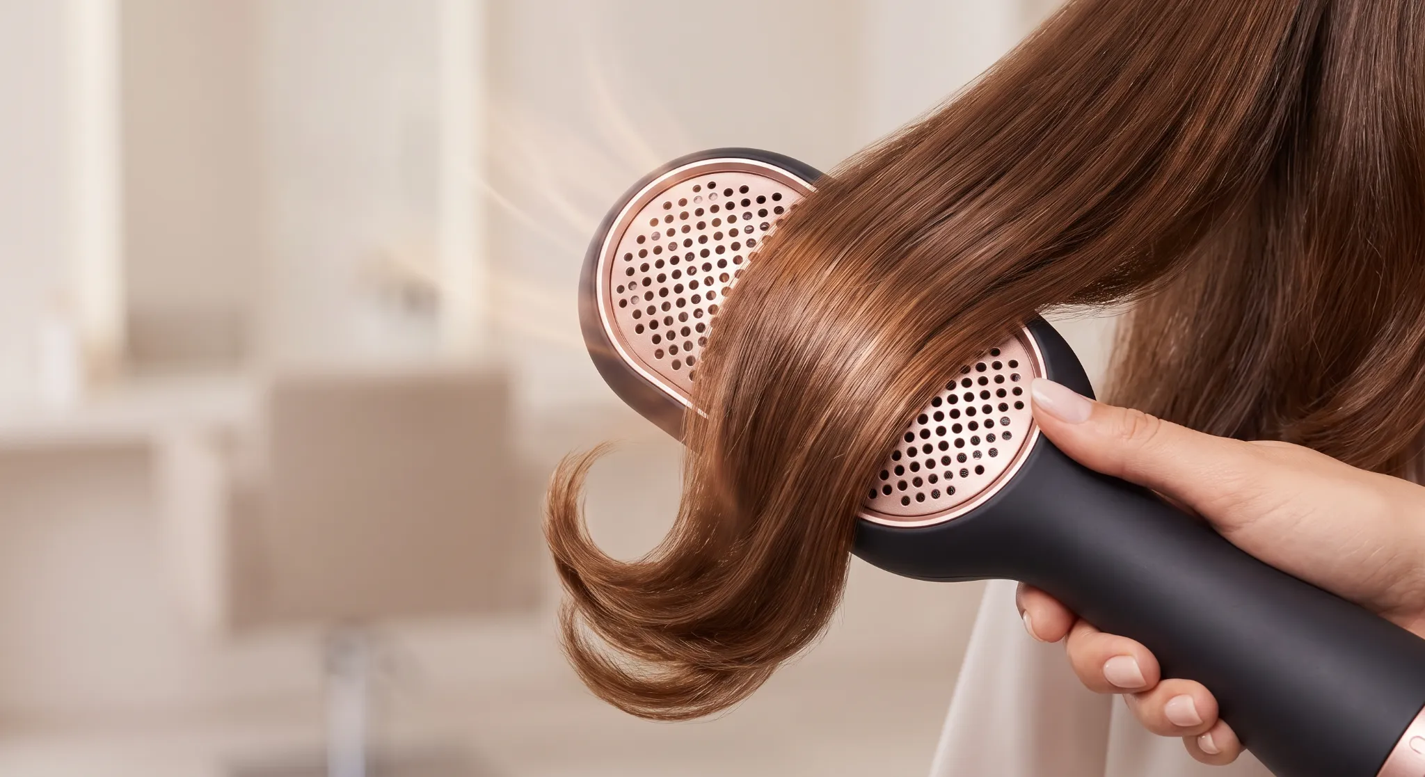 Close-up photograph of an oval ceramic blowout brush smoothing protected swimmer hair on gentle convective heat.