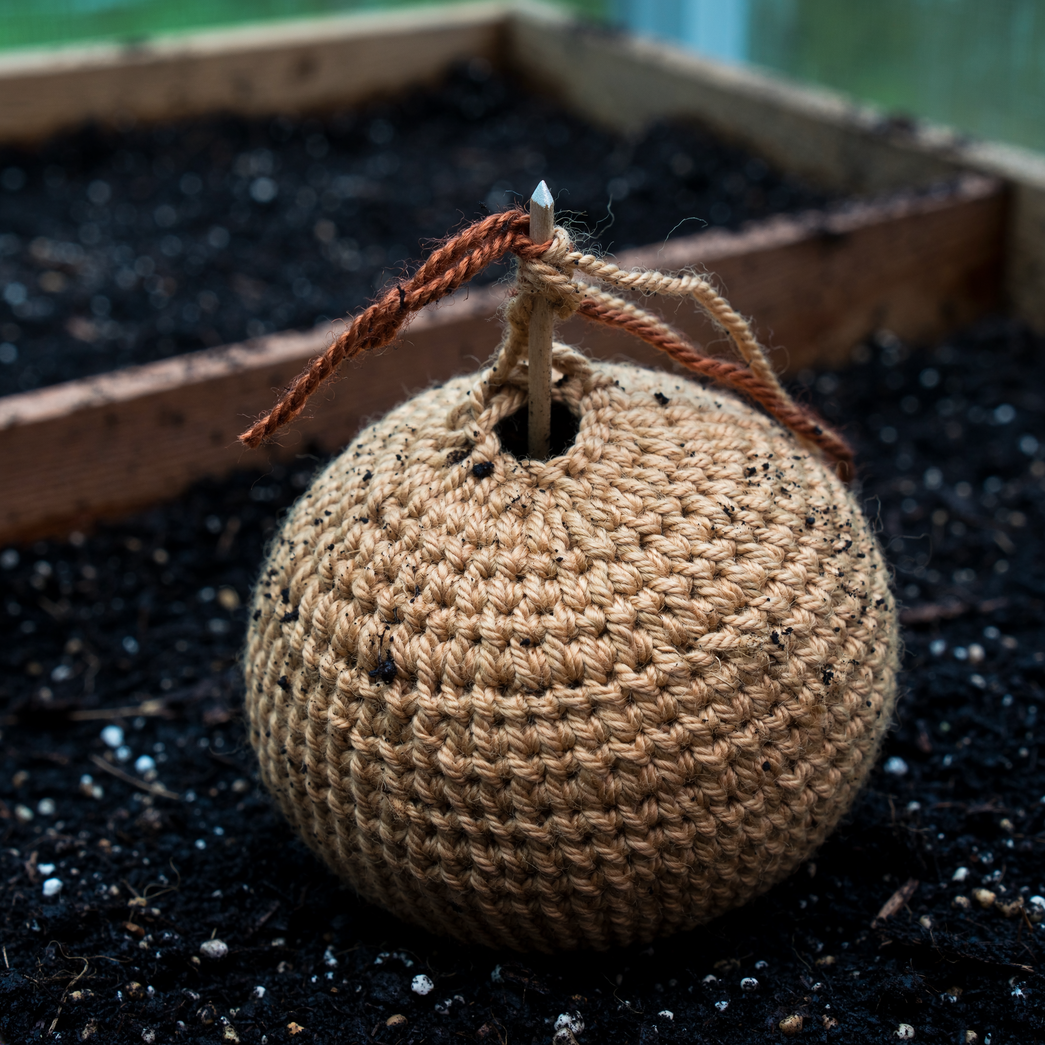 Closed crochet sphere with a short unhidden tail at the pole after the ball is stuffed