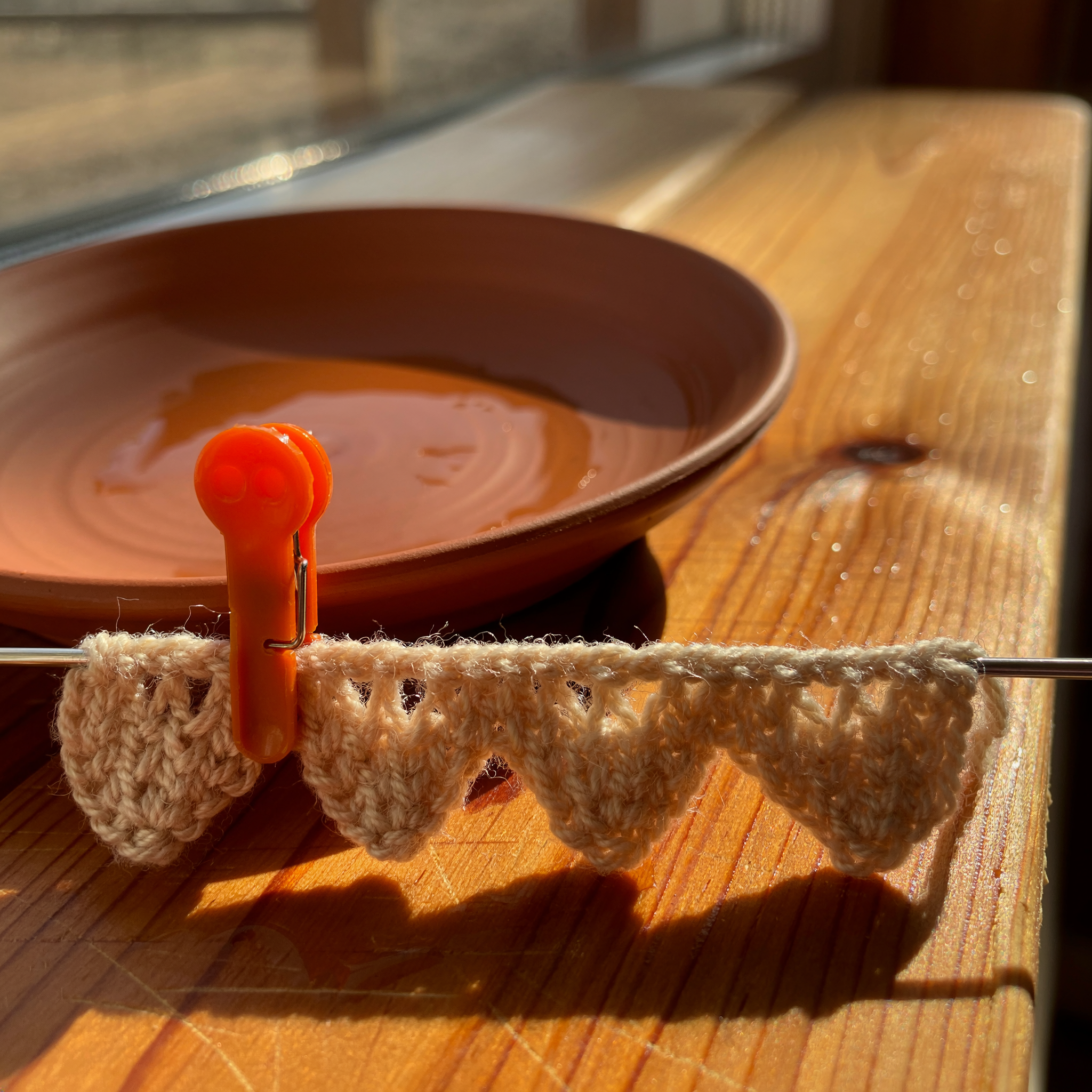 Six even V shapes of a single crochet stitch with one orange locking marker on the last stitch